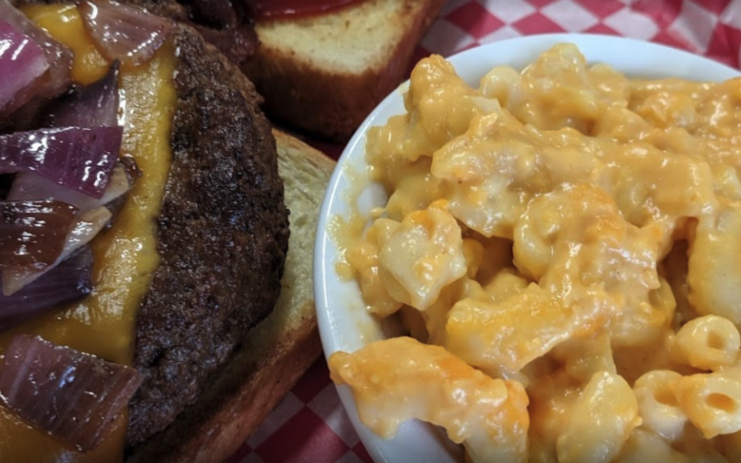 a cheeseburger topped with purple onions, next to a bowl of homemade Mac and cheese