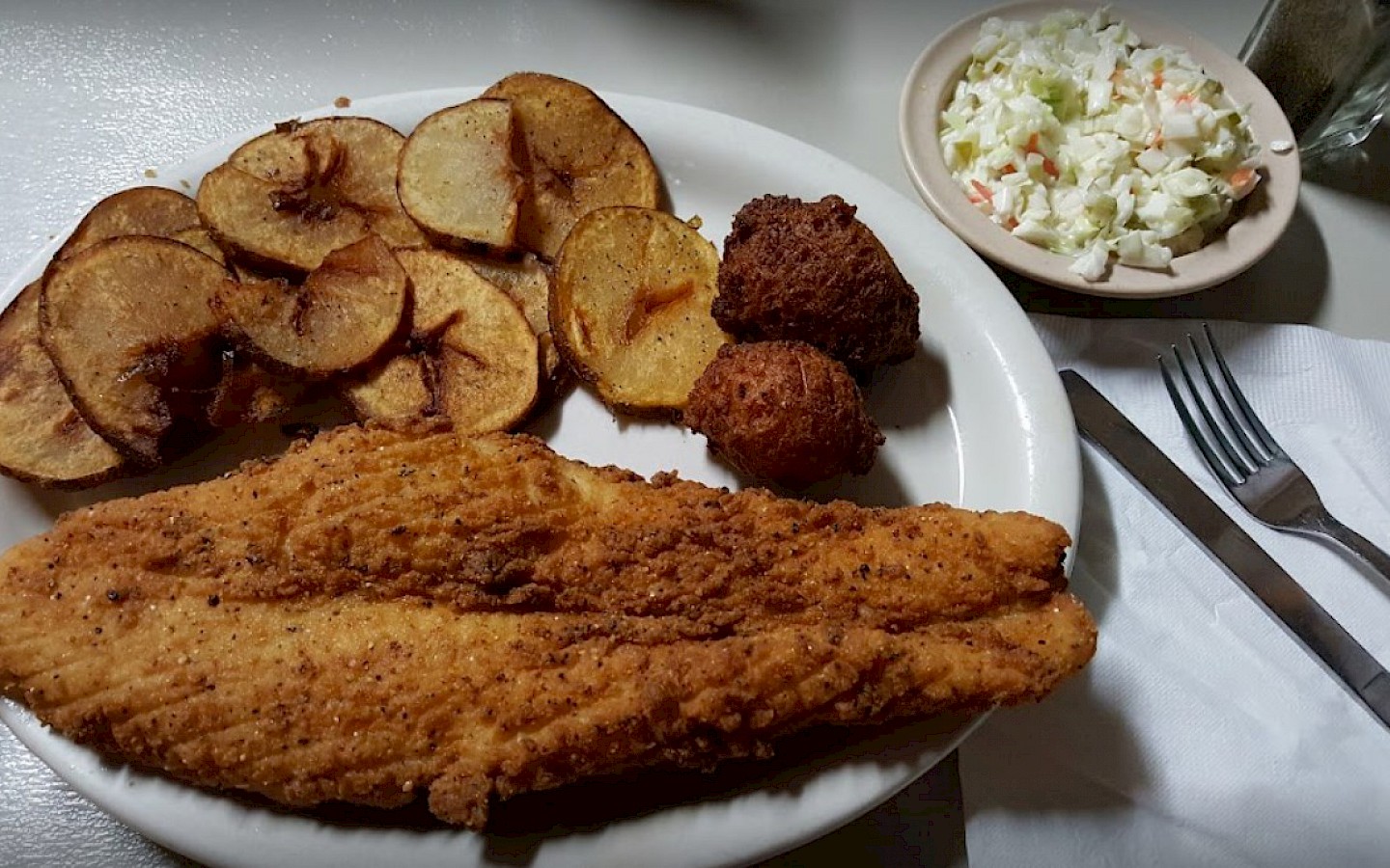fried catfish, French fries, hush puppies, and a bowl of coleslaw