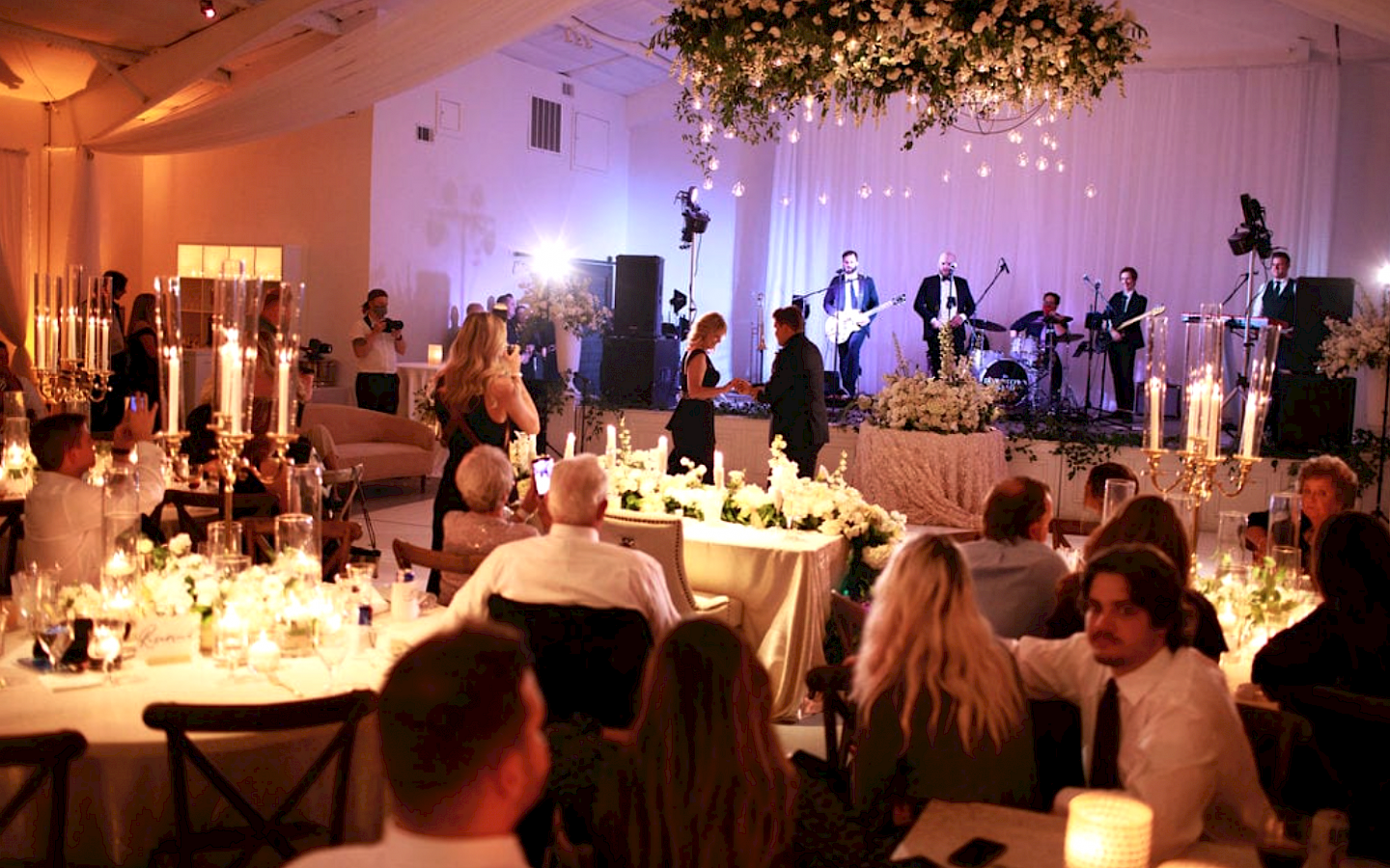 guest set in a romantically lit large room, with a band on stage performing