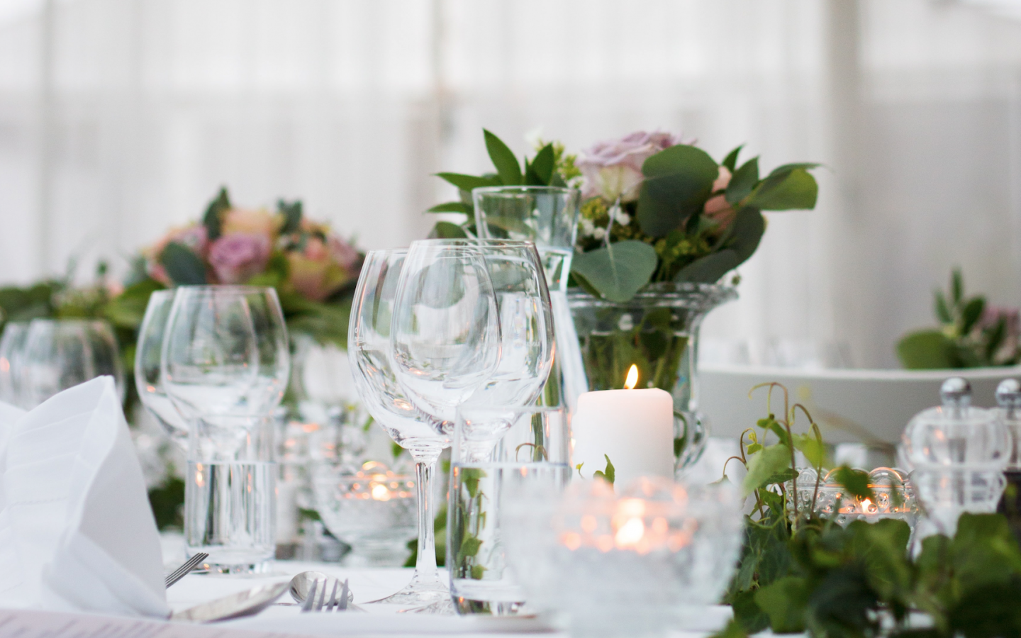 an event table set with flowers, candles, and wine glasses