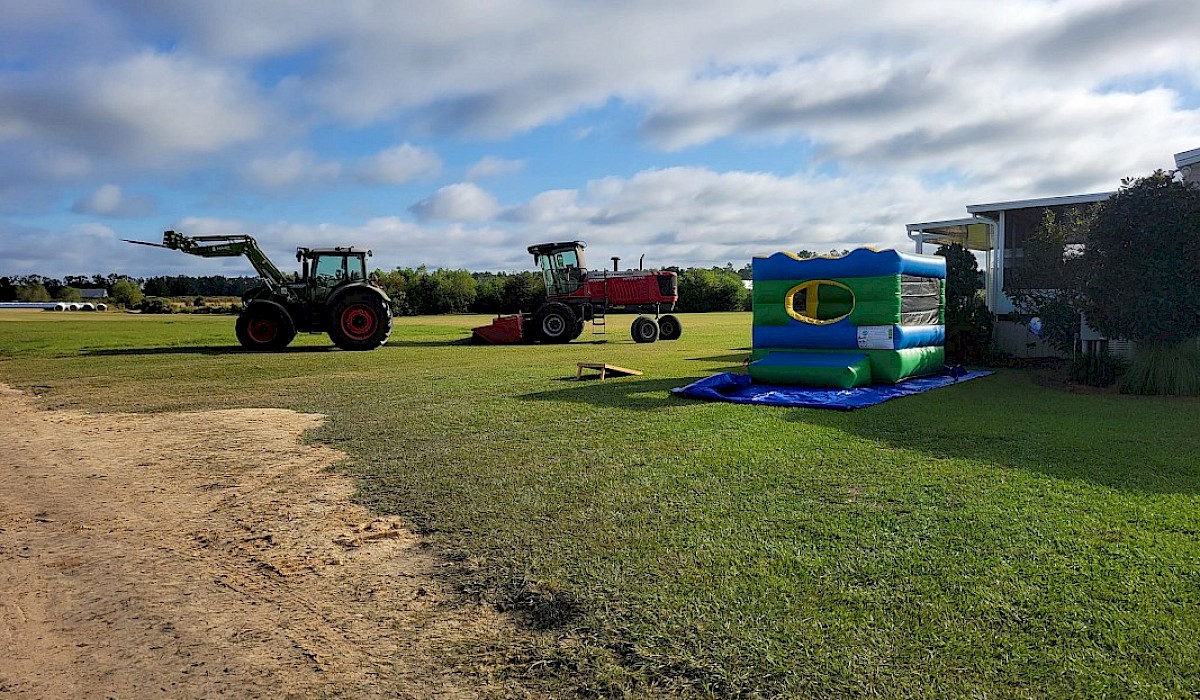 tractors and a bounce house positioned in a field at a beef farm