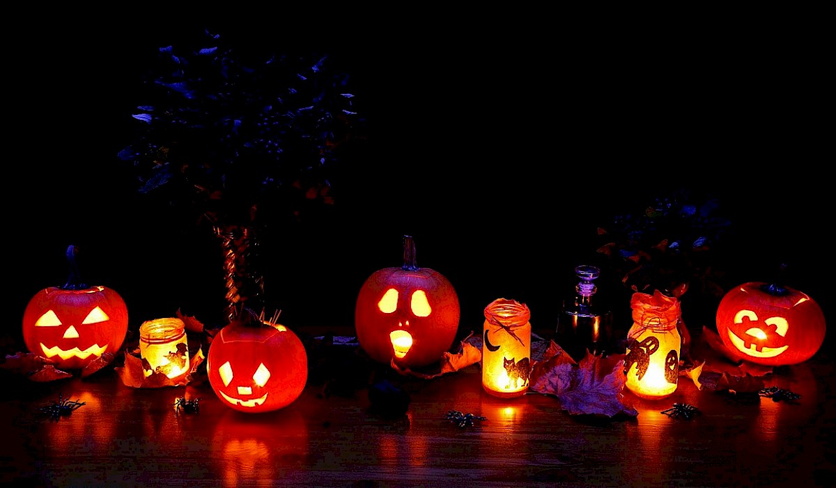 jack-o-lanterns lit by candles along a table in the dark