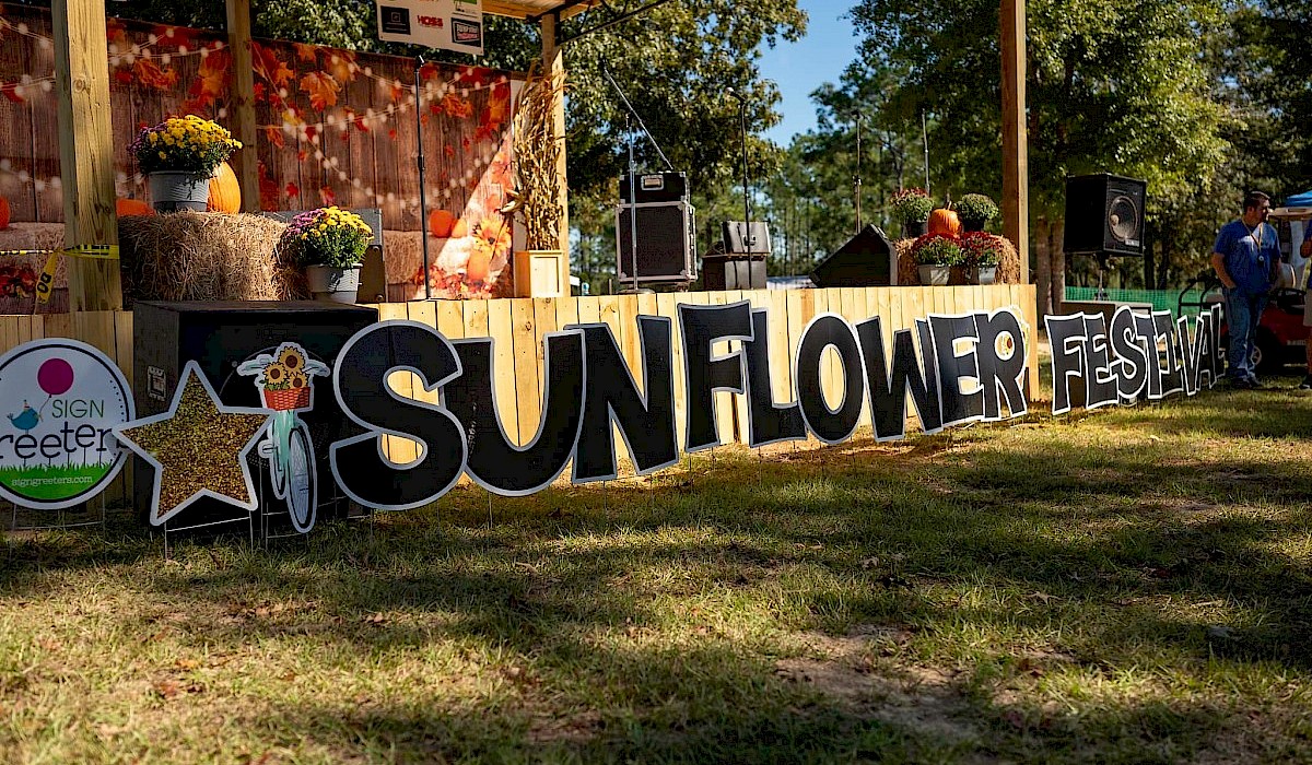 festival stage set in a field with fresh flower arrangements on the sides and a festival banner up front