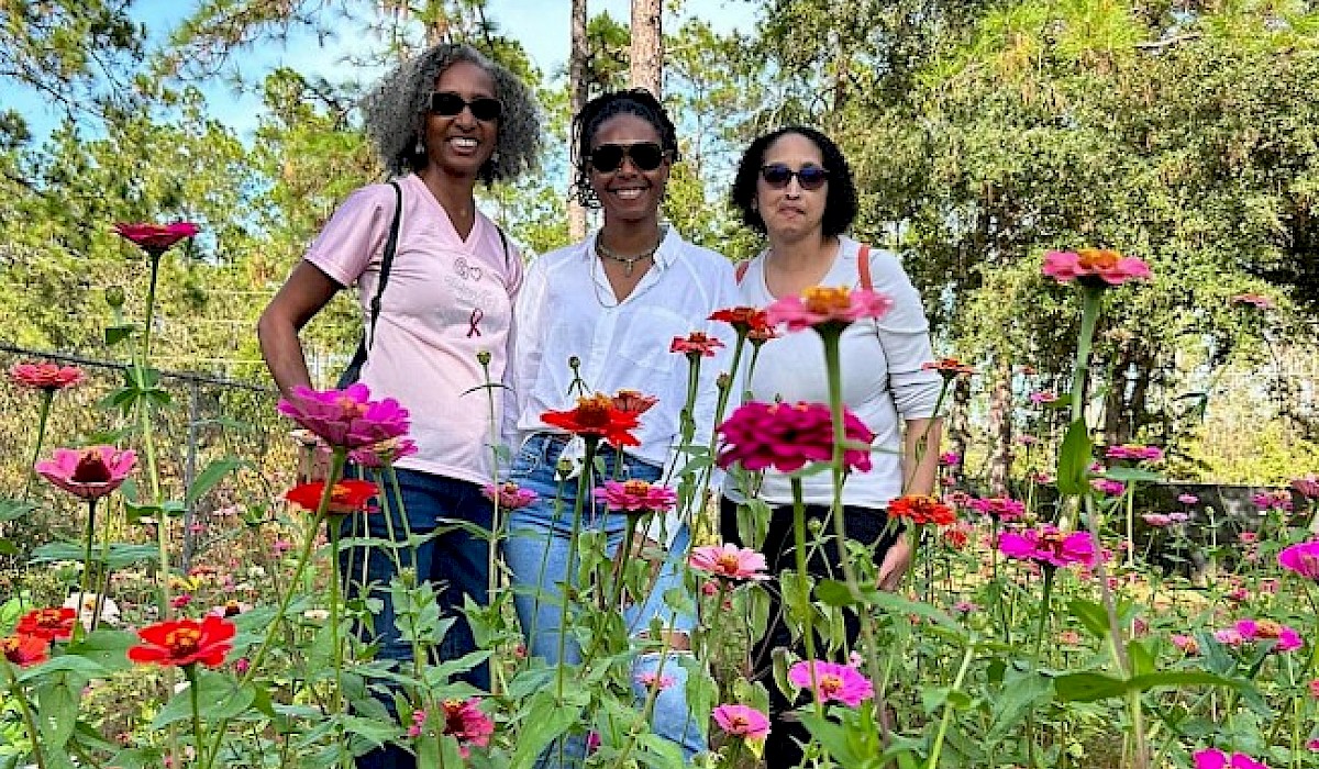 three women posing in a flower field during a festival