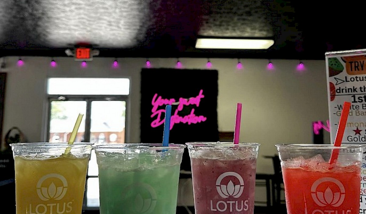 four lotus drinks with straws placed in a row on the counter of a dessert shop