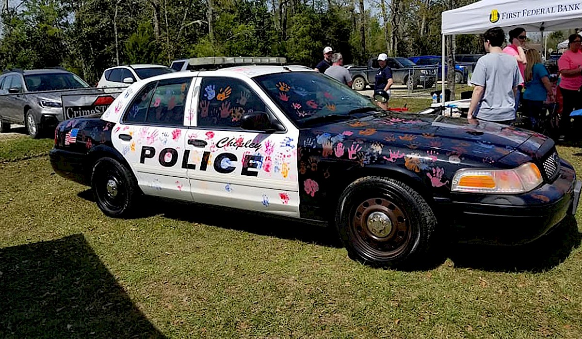 police car with childrens paint hand prints all over it in different colors