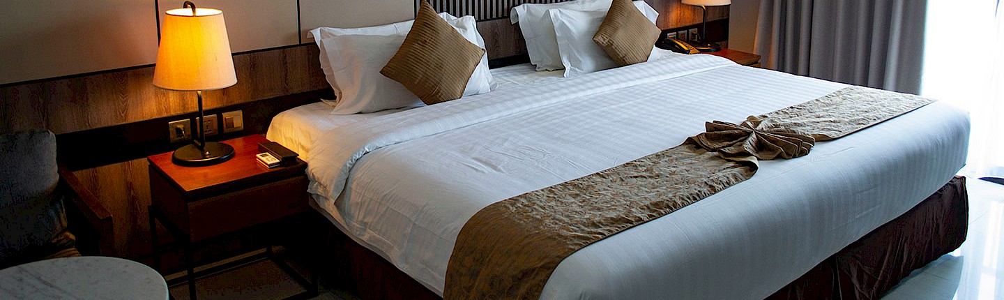 a made-up king side bed of a hotel room